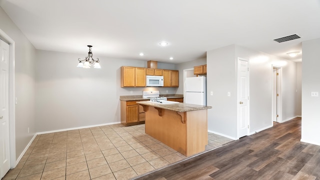 12218 W 10th Ave, Airway Heights, WA 99001 - kitchen featuring white appliances, a kitchen bar, recessed lighting, baseboards, and a center island