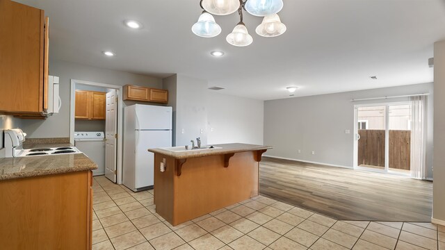 12218 W 10th Ave, Airway Heights, WA 99001 - kitchen with freestanding refrigerator, range, washer / dryer, light tile patterned floors, and open floor plan