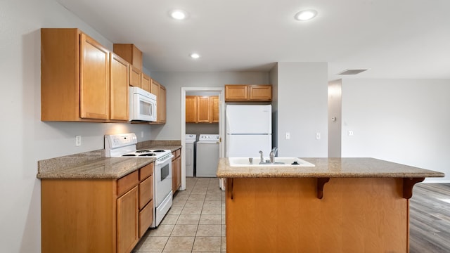 12218 W 10th Ave, Airway Heights, WA 99001 - kitchen with white appliances, washer and clothes dryer, a sink, a breakfast bar area, and a center island with sink