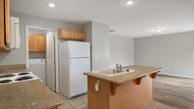 12218 W 10th Ave, Airway Heights, WA 99001 - kitchen with white appliances, washer / clothes dryer, light tile patterned floors, a kitchen breakfast bar, and a center island