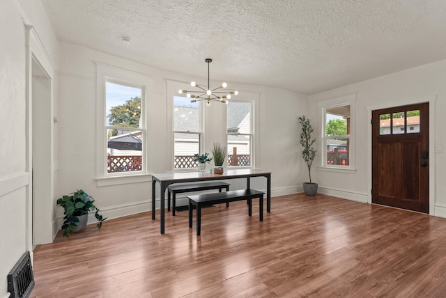 2018 E 6th Ave, Spokane, WA 99202 - dining space featuring a chandelier, a textured ceiling, plenty of natural light, light wood-type flooring, and baseboards