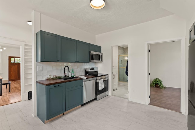 2018 E 6th Ave, Spokane, WA 99202 - kitchen featuring stainless steel appliances, a sink, decorative backsplash, a textured ceiling, and wood counters