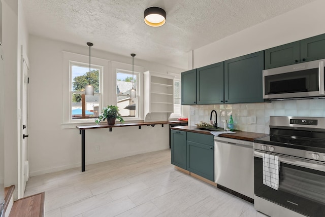2018 E 6th Ave, Spokane, WA 99202 - kitchen with appliances with stainless steel finishes, green cabinets, a sink, decorative backsplash, and a textured ceiling