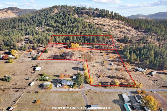 1306 Peachcrest Rd, Kettle Falls, WA 99141 - aerial overview of property's location featuring a mountain backdrop, a heavily wooded area, and property boundaries highlighted