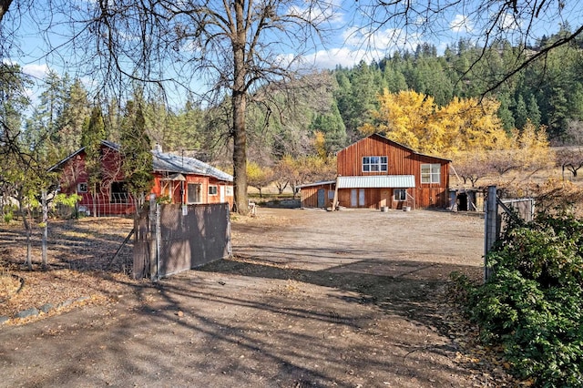 1306 Peachcrest Rd, Kettle Falls, WA 99141 - view of front facade featuring driveway, a wooded view, and a barn