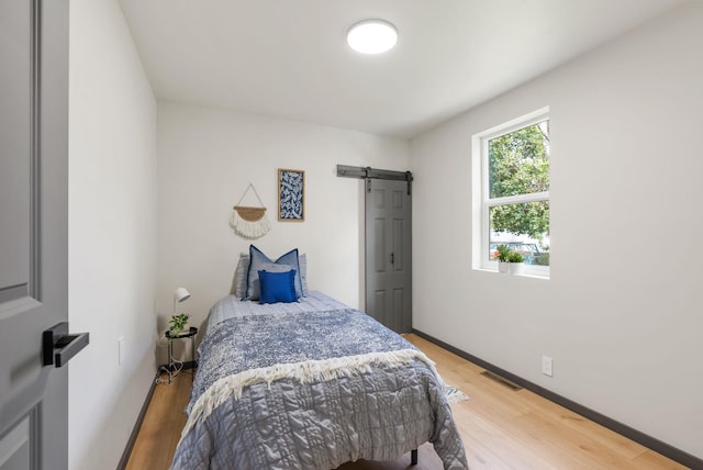 1509 N Lee St, Spokane, WA 99207 - bedroom with a barn door, light wood-style floors, and baseboards