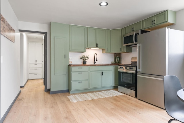 1509 N Lee St, Spokane, WA 99207 - kitchen with green cabinets, appliances with stainless steel finishes, wood counters, light wood finished floors, and a sink
