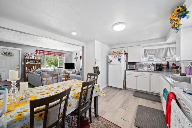 1503 E Dalton Ave, Spokane, WA 99207 - kitchen featuring white appliances, white cabinets, light wood-style flooring, open floor plan, and a textured ceiling