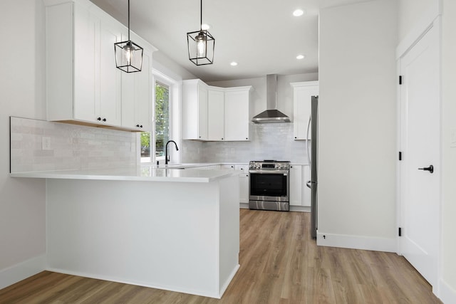 1817 N Arties Rd, Spokane Valley, WA 99016 - kitchen featuring appliances with stainless steel finishes, wall chimney range hood, a peninsula, light wood finished floors, and light countertops