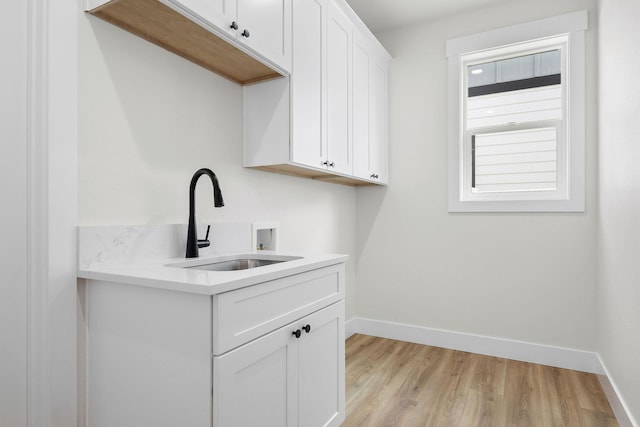 1817 N Arties Rd, Spokane Valley, WA 99016 - washroom with washer hookup, baseboards, light wood-type flooring, and cabinet space