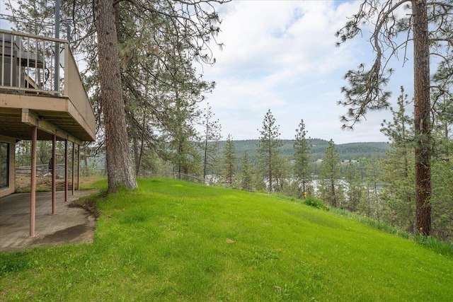 16905 N Mockingbird Ct, Nine Mile Falls, WA 99026 - view of grassy yard with a wooden deck, a wooded view, and a patio area