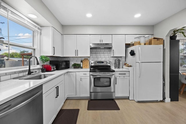 811 E Dalke Ave, Spokane, WA 99208 - kitchen featuring appliances with stainless steel finishes, a sink, light wood-style floors, light countertops, and under cabinet range hood