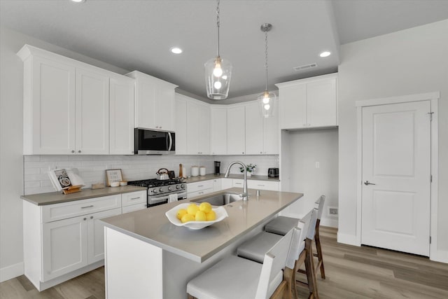 1109 N Country Club Dr Unit 20, Deer Park, WA 99006 - kitchen featuring appliances with stainless steel finishes, a sink, light wood finished floors, backsplash, and white cabinets