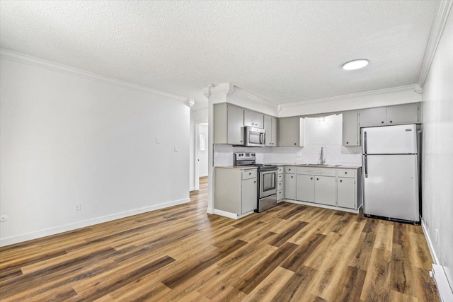 917 E Indiana Ave, Spokane, WA 99207 - kitchen featuring appliances with stainless steel finishes, gray cabinets, a sink, ornamental molding, and dark wood finished floors