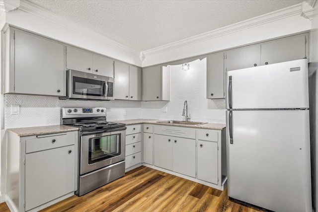 917 E Indiana Ave, Spokane, WA 99207 - kitchen with stainless steel appliances, a sink, ornamental molding, decorative backsplash, and a textured ceiling