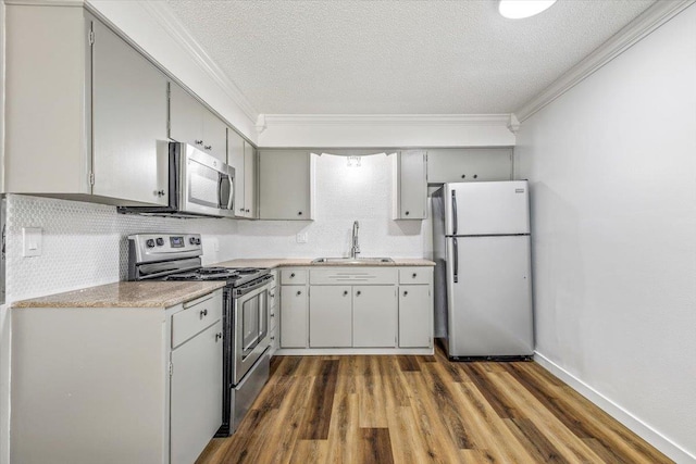 917 E Indiana Ave, Spokane, WA 99207 - kitchen with appliances with stainless steel finishes, a sink, ornamental molding, light countertops, and dark wood-style floors