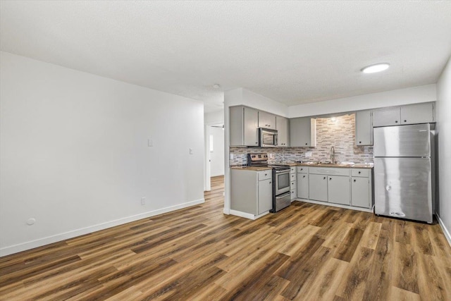 917 E Indiana Ave, Spokane, WA 99207 - kitchen with stainless steel appliances, gray cabinets, tasteful backsplash, and dark wood finished floors