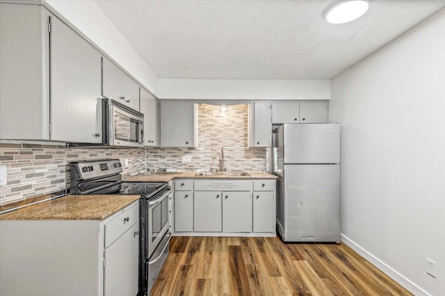 917 E Indiana Ave, Spokane, WA 99207 - kitchen featuring stainless steel appliances, a sink, dark wood-style floors, tasteful backsplash, and a textured ceiling