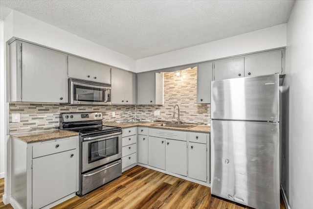 917 E Indiana Ave, Spokane, WA 99207 - kitchen featuring stainless steel appliances, a sink, gray cabinetry, dark wood-type flooring, and a textured ceiling