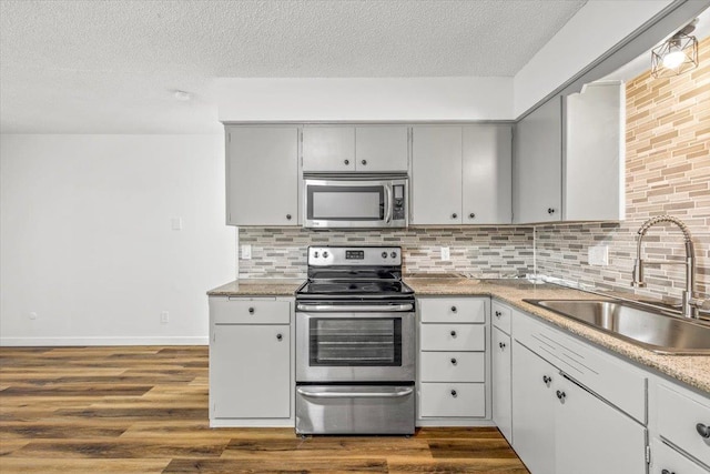 917 E Indiana Ave, Spokane, WA 99207 - kitchen with stainless steel appliances, a sink, a textured ceiling, tasteful backsplash, and dark wood-style flooring