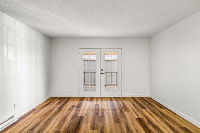 917 E Indiana Ave, Spokane, WA 99207 - spare room with a baseboard radiator, wood finished floors, french doors, baseboards, and a textured ceiling