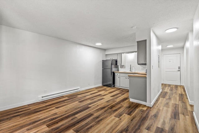 917 E Indiana Ave, Spokane, WA 99207 - kitchen featuring freestanding refrigerator, baseboard heating, a sink, dark wood-style flooring, and a textured ceiling