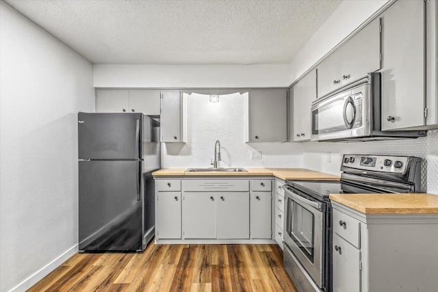 917 E Indiana Ave, Spokane, WA 99207 - kitchen with appliances with stainless steel finishes, a sink, wood finished floors, light countertops, and a textured ceiling