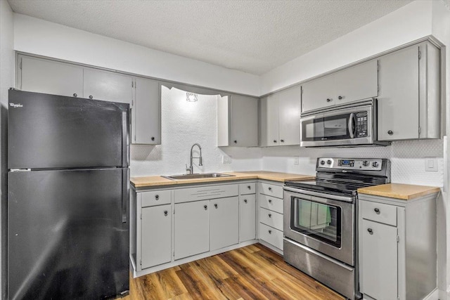 917 E Indiana Ave, Spokane, WA 99207 - kitchen with appliances with stainless steel finishes, a sink, gray cabinetry, dark wood finished floors, and light countertops
