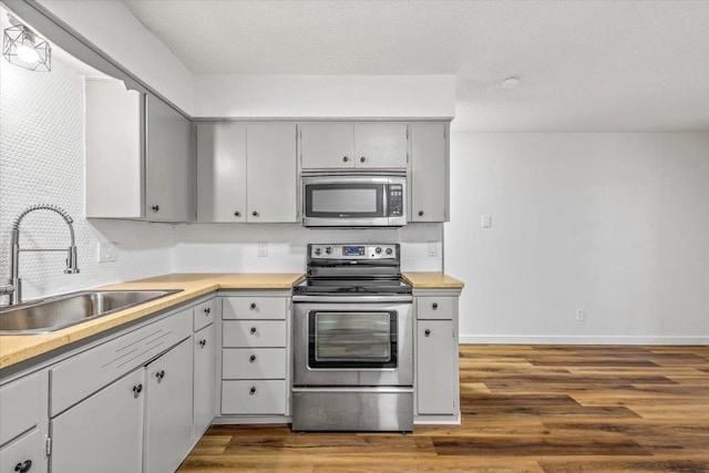 917 E Indiana Ave, Spokane, WA 99207 - kitchen with stainless steel appliances, a sink, dark wood-type flooring, gray cabinetry, and light countertops