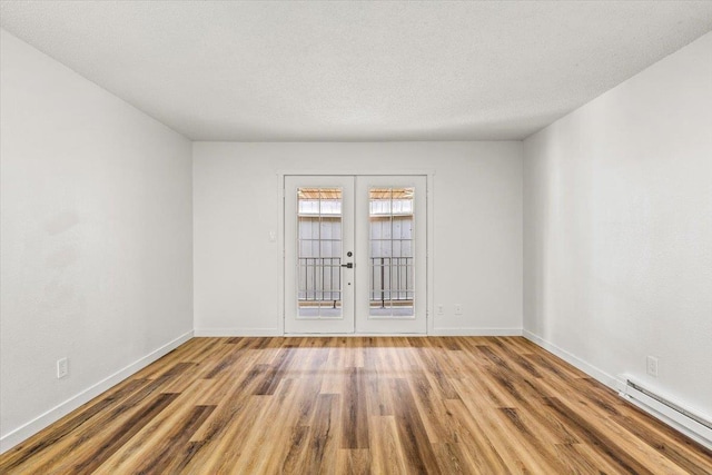 917 E Indiana Ave, Spokane, WA 99207 - unfurnished room featuring a baseboard heating unit, french doors, wood finished floors, baseboards, and a textured ceiling