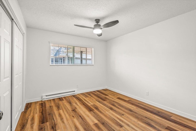 917 E Indiana Ave, Spokane, WA 99207 - unfurnished bedroom with baseboard heating, a closet, wood finished floors, a textured ceiling, and baseboards