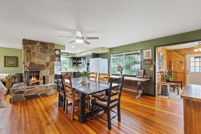 3720 E Bridges Rd, Elk, WA 99009 - dining area with a ceiling fan, light wood-style floors, a textured ceiling, a fireplace, and wood walls