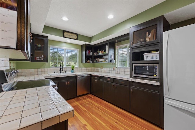 3720 E Bridges Rd, Elk, WA 99009 - kitchen with appliances with stainless steel finishes, tile countertops, a sink, light wood-type flooring, and plenty of natural light
