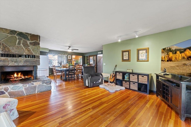 3720 E Bridges Rd, Elk, WA 99009 - living area with wood-type flooring, a stone fireplace, ceiling fan, and rail lighting