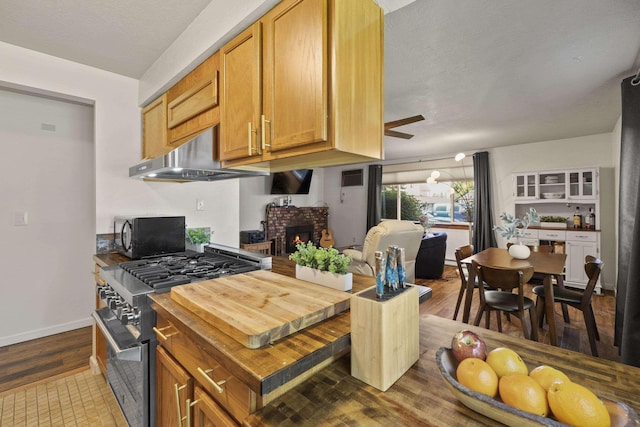112 E Weile Ave Unit # 1, Spokane, WA 99208 - kitchen with black microwave, high end stainless steel range, under cabinet range hood, a brick fireplace, and baseboards