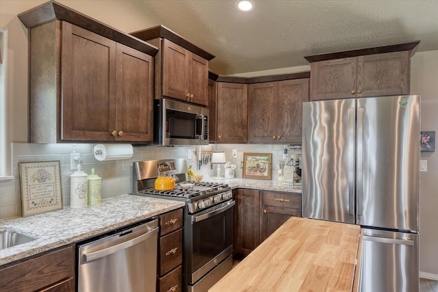 8202 W Quaking Rd, Spokane, WA 99224 - kitchen with appliances with stainless steel finishes, backsplash, butcher block counters, and dark brown cabinetry