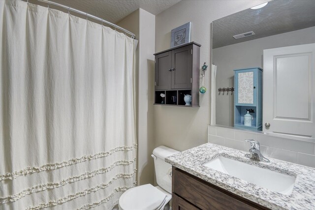 8202 W Quaking Rd, Spokane, WA 99224 - bathroom featuring toilet, tasteful backsplash, vanity, and a textured ceiling