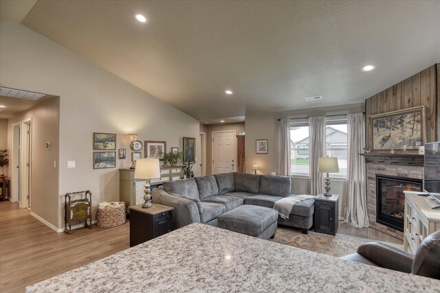 8202 W Quaking Rd, Spokane, WA 99224 - living room with light wood-style flooring, vaulted ceiling, a stone fireplace, recessed lighting, and baseboards