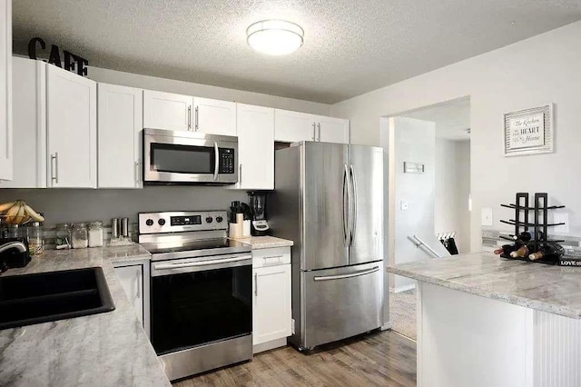 512 N Bessie Rd, Spokane, WA 99212 - kitchen with stainless steel appliances, a textured ceiling, white cabinetry, a sink, and light wood-style flooring