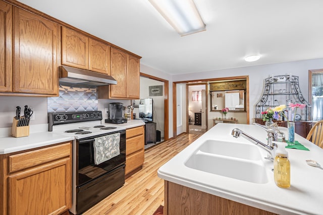 202 W Columbia Ave, Spokane, WA 99205 - kitchen with under cabinet range hood, range with electric stovetop, a sink, light wood-style floors, and light countertops