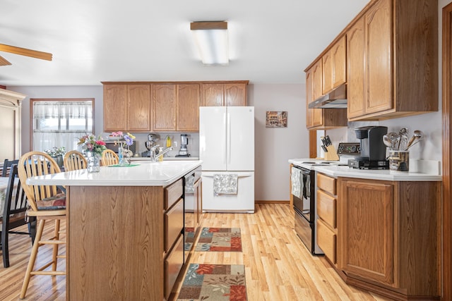 202 W Columbia Ave, Spokane, WA 99205 - kitchen featuring range with electric stovetop, freestanding refrigerator, under cabinet range hood, light countertops, and a kitchen breakfast bar