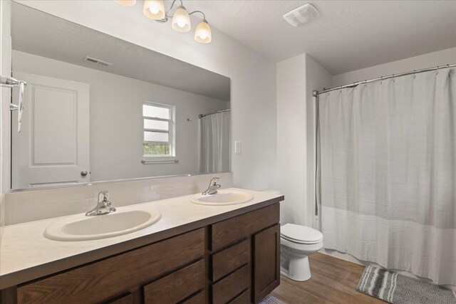 8620 W 8th Ave, Spokane, WA 99224 - bathroom featuring wood finished floors, double vanity, toilet, and tasteful backsplash