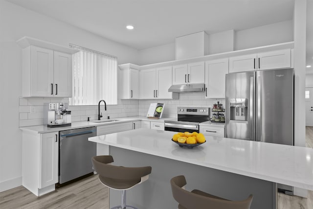 3617 E 1st Ave, Spokane, WA 99202 - kitchen with stainless steel appliances, under cabinet range hood, light wood-style flooring, a breakfast bar area, and recessed lighting