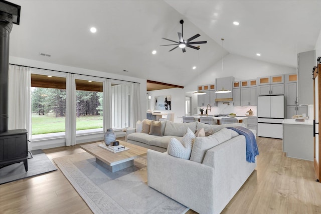 1399 W Findley Ln, Deer Park, WA 99006 - living room with a wood stove, a ceiling fan, high vaulted ceiling, light wood-style flooring, and a barn door