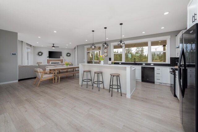 5125 N Ellie Ln, Spokane, WA 99217 - kitchen with black appliances, open floor plan, a breakfast bar, a ceiling fan, and recessed lighting