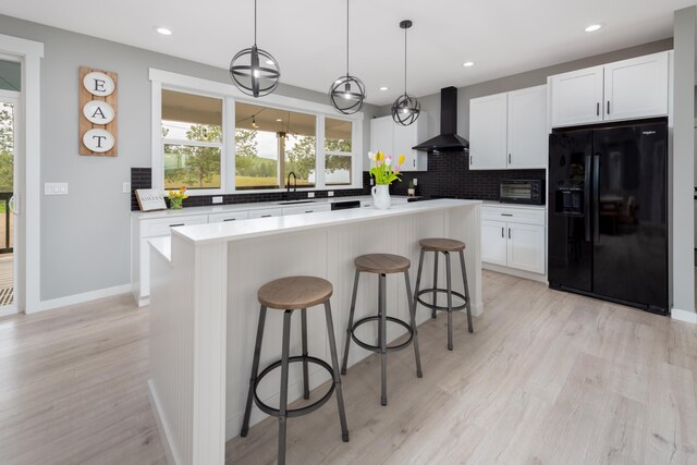 5125 N Ellie Ln, Spokane, WA 99217 - kitchen featuring black refrigerator with ice dispenser, wall chimney exhaust hood, healthy amount of natural light, a breakfast bar area, and recessed lighting