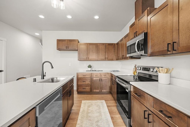 202 S Union Road Building B, Unit 102, Spokane, WA 99206 - kitchen with stainless steel appliances, a sink, light wood-style flooring, brown cabinetry, and light countertops