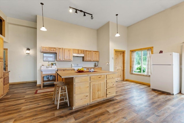 2559F United Copper Mine Rd, Chewelah, WA 99109 - kitchen featuring white appliances, a towering ceiling, light brown cabinets, baseboards, and under cabinet range hood