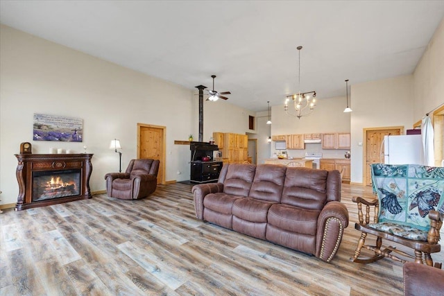 2559F United Copper Mine Rd, Chewelah, WA 99109 - living room with a high ceiling, ceiling fan, light wood-style flooring, a chandelier, and a glass covered fireplace