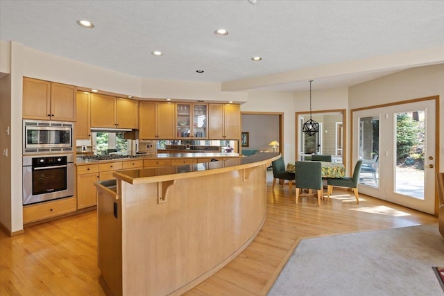 14410 E 45th Ct, Veradale, WA 99037 - kitchen featuring appliances with stainless steel finishes, a kitchen bar, glass insert cabinets, light wood-style floors, and recessed lighting